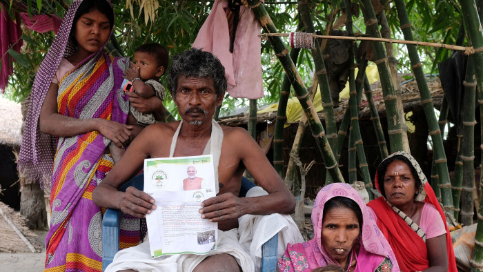 Nand Lal Mandhji, holds a letter about the Ayushman Bharat Medical Scheme, known as 'Modicare' as he sits outside his home with his family in Marwan village in the eastern state of Bihar, India, June 20, 2019. Picture taken June 20, 2019. REUTERS/Alasdair Pal - RC1252E27050
