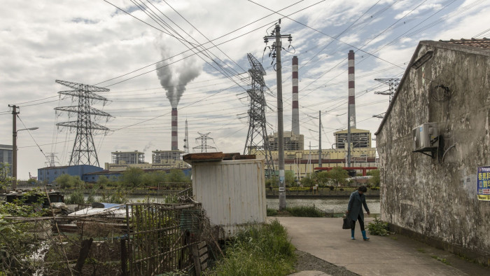 A woman walks past a village house near a coal-fired power station on the outskirts of Ningbo, Zhejiang Province, China, on Wednesday, April 22, 2020. China's top leaders softened their tone on the importance of reaching specific growth targets this year during the latest Politburo meeting on April 17, saying the nation is facing &quot;unprecedented&quot; economic difficulty and signaling that more stimulus was in the works. Photographer: Qilai Shen/Bloomberg