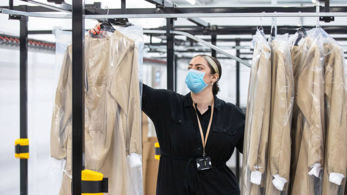 A worker handles completed protective gowns for workers in the U.K. National Health Service (NHS) sit on a rail at the Burberry Group Plc factory in Castleford, U.K., on Tuesday, April 21, 2020. The U.K. ran the risks running out of protective equipment for its hospital staff as half the doctors working in high-risk areas reported supply shortages in an April survey by the British Medical Association. Photographer: Chris Ratcliffe/Bloomberg