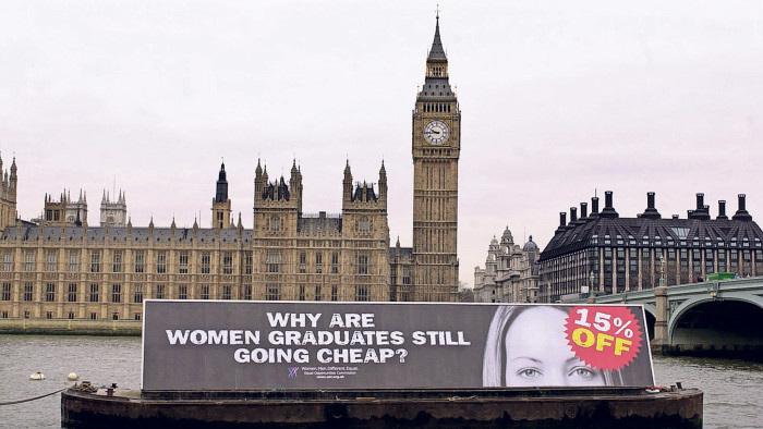 A barge with the slogan 'Why are women graduates still going cheap?' and a picture of a woman with a '15% off' sticker over her face is towed along the River Thames opposite the Houses of Parliament in central London.