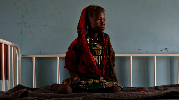 A young girl who is sick sits on a bed in teh children's ward in the health clinic in  Baga Sola, Chad Tuesday, Oct. 4, 2016. 