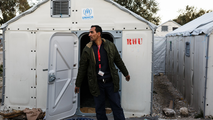 Mohamed stands outside a refugee housing unit at the Kara Tepe accommodation facility where he volunteers as an electrician along with his brother Mofeed. ; Mohamed Dhib, 44, is an electrician and plumber with a university degree in archaeology. He came to the Greek island of Lesbos in April 2016 with his wife, four children and his brother, after fleeing the war in Syria. The family of seven crossed the Aegean Sea from Turkey on an inflatable boat and were intercepted by coast guards. After being granted asylum by the Greek authorities the family lives in a house provided by UNHCR, through local partner Iliaktida, who provide accommodation for asylum-seekers. Mohamed volunteers as an electrician at the Kara Tepe accommodation facility where he installs electric power lines and solar panels on prefabricated houses that are being built to upgrade the facility.