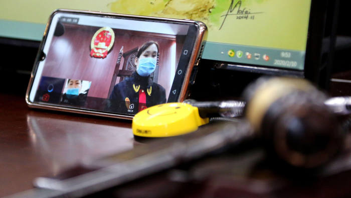 2AX9C7F A Chinese judge hears and tries a case on her smartphone through the Internet at a local court for prevention of the new coronavirus and pneumonia in