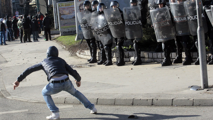 A demonstrator holds a stone in front riot police in Bosnia