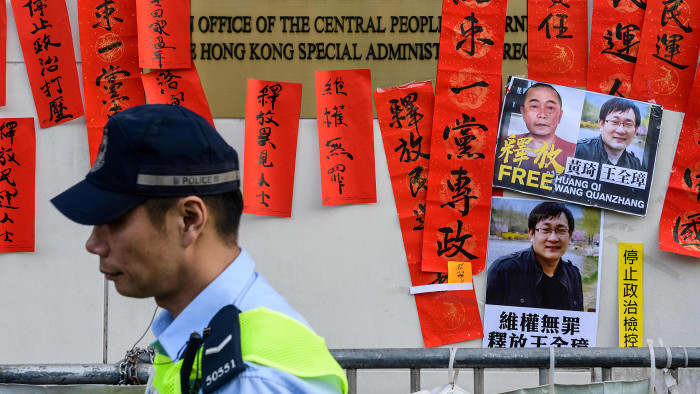 Police walk past messages in support of jailed Chinese human rights lawyer Wang Quanzhang (pictured R on placard) and China's first &quot;cyber-dissident&quot; and founder of human rights website &quot;64 Tianwang&quot;, Huang Qi (pictured L on placard), after a protest attended by Hong Kong pro-democracy activists outside the Chinese Liaison Office in Hong Kong on January 29, 2019. - Prominent Chinese human rights lawyer Wang Quanzhang was sentenced on January 28 to four and a half years in prison for state subversion, sealing the fate of another attorney swept up in a 2015 crackdown. (Photo by Anthony WALLACE / AFP) (Photo credit should read ANTHONY WALLACE/AFP/Getty Images)