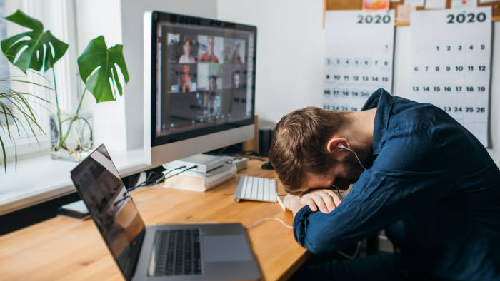 Riga, Latvia - March 28 2020: Tired businessman sleeping on his work desk while having a video call via a computer in the home office. Remote team meeting video online conference Exhausting Calls; Shutterstock ID 1705987216; Department: -; Job/Project: -; Employee Name: -