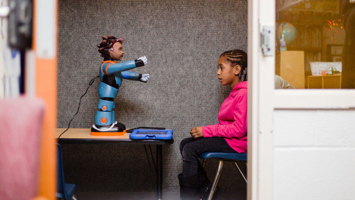 Destiny Ragin, 7, listens intently as Milo, the robot, gives her instructions for an exercise they will do together.