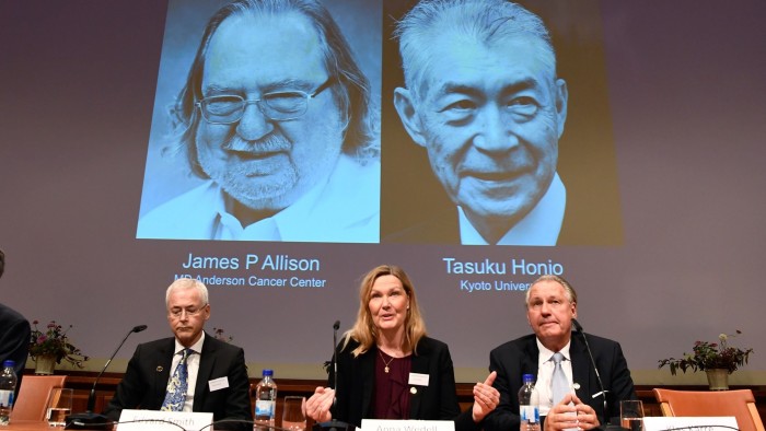 Members of the Nobel Committee for Physiology or Medicine (L-R) Jonas Bergh, Edvard Smith, Anna Wedell and Klas Kaerre sit in front of a screen displaying portraits of James P Allison (L) and Tasuku Honjo during the announcement of the winners of the 2018 Nobel Prize in Physiology or Medicine, during a press conference at the Karolinska Institute in Stockholm, Sweden, on October 1, 2018. - James P Allison of US and Tasuku Honjo of Japan won Nobel Medicine Prize for their achievements in cancer treatment. (Photo by Jonathan NACKSTRAND / AFP)JONATHAN NACKSTRAND/AFP/Getty Images