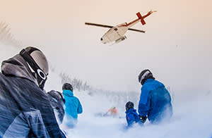 Skiers waiting for a Bell 212 to pick them up