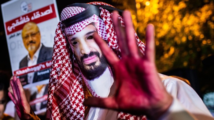 A protestor wears a mask of depicting Saudi Crown Prince Mohammad Bin Salman with red painted hands next to people holding posters of Saudi journalist Jamal Khashoggi during the demonstration outside the Saudi Arabia consulate in Istanbul, on October 25, 2018. - Jamal Khashoggi, a Washington Post contributor, was killed on October 2, 2018 after a visit to the Saudi consulate in Istanbul to obtain paperwork before marrying his Turkish fiancee. (Photo by Yasin AKGUL / AFP)YASIN AKGUL/AFP/Getty Images