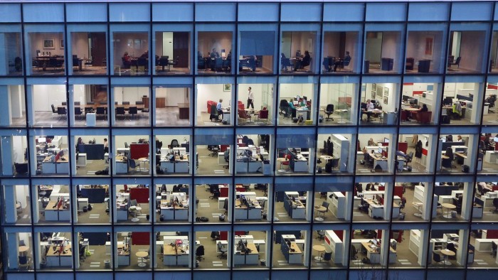 People work at dusk on various floors of a modern office development
