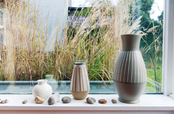 Denby and Poole pottery with beach pebbles on a shelf
