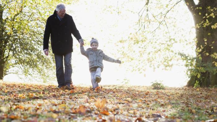 Grandfather walking outdoors with grandson in autumn