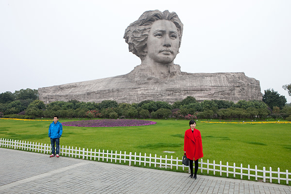 Two tourists pose for a photograph in front of a statue of the young Mao Zedong in the Changsha, Hunan province