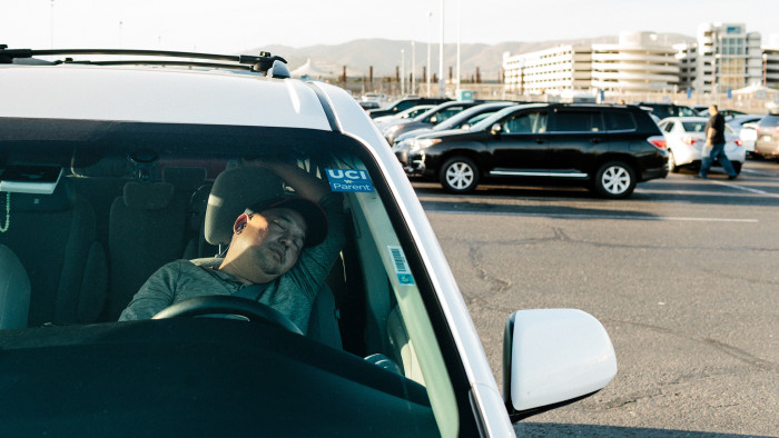 A man naps in his car at the TNC airport waiting lot for Uber and Lyft drivers in San Francisco, Calif., Sunday October 1, 2017.
