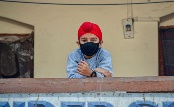 A boy wearing a protective mask ventures on to a balcony in Srinagar, which recorded Kashmir's first coronavirus death in late March