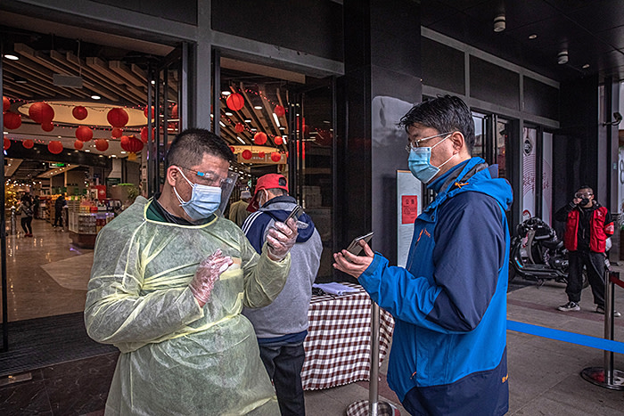 epa08334193 A worker in a protective outfit checks health QR codes of a man at the entrance of a shopping mall in Wuhan, China, 31 March 2020. Chinese authorities have partly lifted the lockdown of Wuhan -- the city that saw the first cases of the novel coronavirus disease (COVID-19), which is caused by the SARS-CoV-2 virus that has now spread all over the world and declared as a pandemic -- and are allowing people to enter the city after more than two months of restrictions. The easing of the quarantine measures comes as new COVID-19 infections across China have plummeted, according to Chinese government reports. EPA-EFE/ROMAN PILIPEY