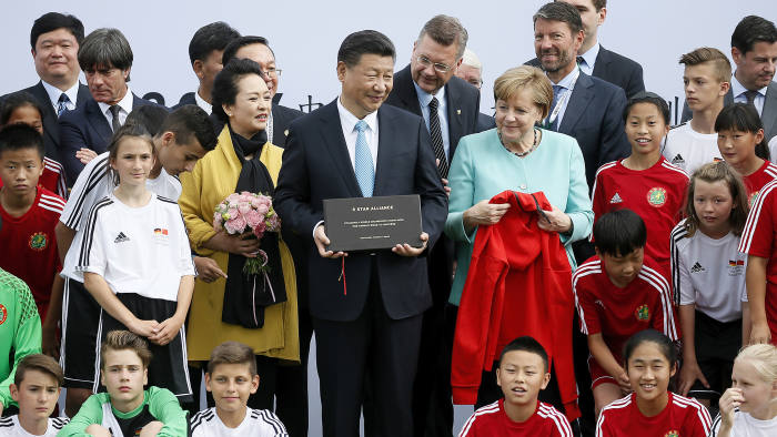 epa06067969 Chinese President Xi Jinping and his wife Peng Liyuan and German Chancellor Angela Merkel get gifts by U12 children of Germany and China during their visit in Olympic Park in Berlin, Germany, 05 July 2017. Chancellor Angela Merkel and the Chinese President of the People's Republic of China, Xi Jinping, will be informing about the current status of cooperation in the field of football at the Olympic Park in Berlin. EPA/RONALD WITTEK / POOL
