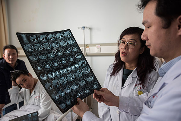 Doctor Shao Yingmei, second right, and a colleague check a scan of the torso of Aga, a Tibetan herder