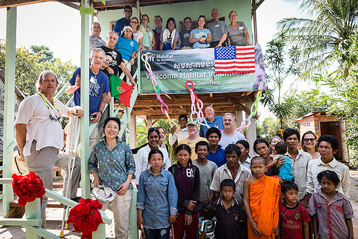 Yot Sat and Phit Pik’s family with Habitat volunteers and Yuan Yang, at the foot of the stairs, outside their new house