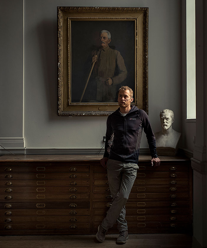 Houlding in the Map Room of the Royal Geographical Society, in front of a portrait of Sir Henry Morton Stanley and bust of James Augustus Grant, both former fellows