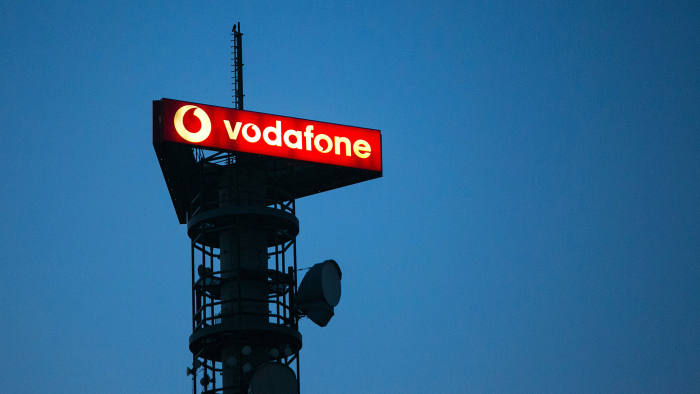 The Vodafone Group Plc logo sits illuminated on top of a telecommunications mast in Berlin, Germany, on Thursday, Nov. 5, 2015