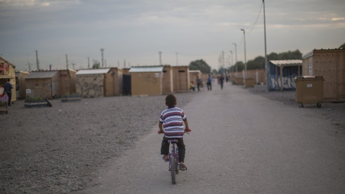 A boy cycles through the Grande-Synthe camp in Dunkirk