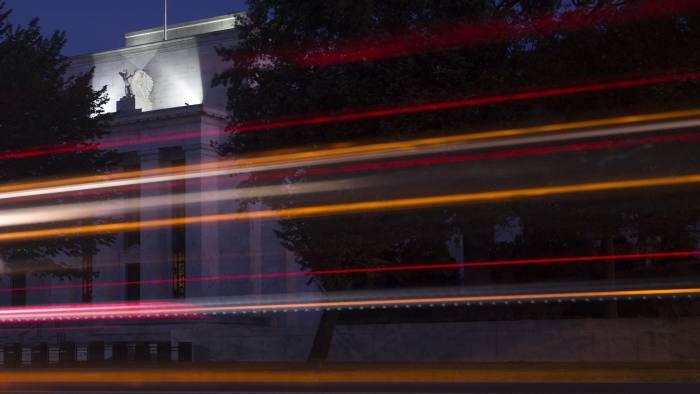 The Marriner S. Eccles Federal Reserve building stands past moving vehicles in Washington, D.C., U.S., on Tuesday, Sept. 15, 2015. While economists are almost equally divided on whether Federal Reserve chair Janet Yellen will raise U.S. interest rates this week, the bond market suggests policy makers will wait. Photographer: Andrew Harrer/Bloomberg