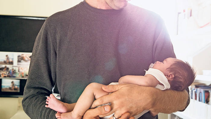 Father holding newborn baby in bedroom