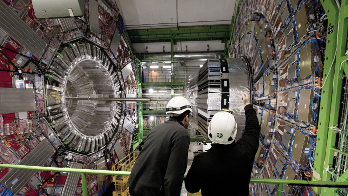 Workers gesture on February 10, 2015 in front of the CMS (Compact Muon Solenoid) Cavern at the European Organisation for Nuclear Research (CERN) in Meyrin, near Geneva