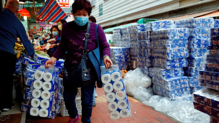 FILE PHOTO: File picture of a customer picking up rolls of toilet paper at a Hong Kong market following the coronavirus outbreak February 8, 2020. REUTERS/Tyrone Siu/File Photo