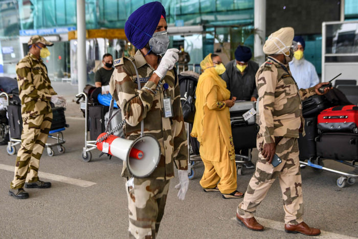 Central Industrial Security Force (CISF) personnel patrol as British nationals queueing before checking-in for a special flight to London after the government eased a nationwide lockdown imposed as a preventive measure against the COVID-19 coronavirus, at Sri Guru Ram Das Ji International Airport on the outskirts of Amritsar on May 13, 2020. (Photo by NARINDER NANU / AFP) (Photo by NARINDER NANU/AFP via Getty Images)