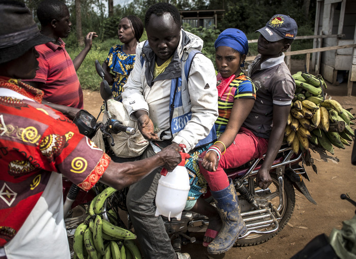A motor taxi driver and his clients get their hands washed at an Ebola screening station before entering the city of Beni on July 13, 2019.