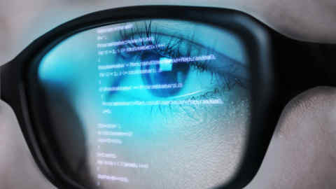 Programming code of computer monitor reflect to her eyeglasses.
