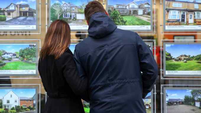 A couple look at houses for sale in the window of William H Brown estate agents in this arranged photograph in Chelmsford, U.K., on Tuesday, Dec. 15, 2015. U.K. asking prices rose an annual 7.4 percent in December amid a continuing shortage of homes for sale, according to Rightmove. Photographer: Chris Ratcliffe/Bloomberg