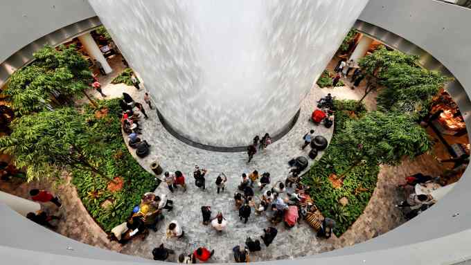 SINGAPORE - APRIL 11: Visitors take photo of the Rain Vortex, a 40 metres high largest indoor waterfall in the world as the sky trains ride past at the Jewel Changi Airport on April 11, 2019 in Singapore. Officially opening on April 17, Singapore's Changi Airport Jewel includes a 40-meter indoor waterfall contained under a steel-and-glass dome reportedly built for SGD 1.7 billion. (Photo by Suhaimi Abdullah/Getty Images)