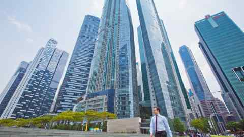 A pedestrian walks in front of commercial buildings in the central business district of Singapore, on Friday, April 8, 2016. Singapore edged past Hong Kong as the worlds No. 3 financial center. The Southeast Asian city-state ranks behind London and New York on the Global Financial Centres Index, according to a survey by London-based research firm Z/Yen Group. Photographer: Sam Kang Li/Bloomberg