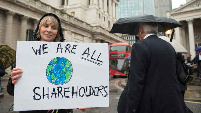 LONDON, ENGLAND - OCTOBER 14: An Extinction Rebellion protester holds up a placard saying "We are all shareholders" as they block the roads outside the Bank of England on October 14, 2019 in London, England. The protest targets the financial district for its investments in fossil fuels, part of an ongoing two week London protest targeting key Government locations in central London through non violent protests. (Photo by John Keeble/Getty Images)