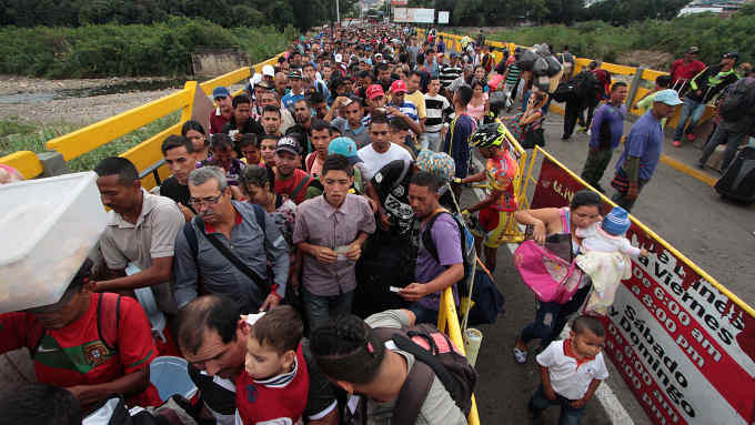 TOPSHOT - Venezuelan citizens cross the Simon Bolivar international bridge from San Antonio del Tachira in Venezuela to Norte de Santander province of Colombia on February 10, 2018. Oil-rich and once one of the wealthiest countries in Latin America, Venezuela now faces economic collapse and widespread popular protest. / AFP PHOTO / GEORGE CASTELLANOS (Photo credit should read GEORGE CASTELLANOS/AFP/Getty Images)