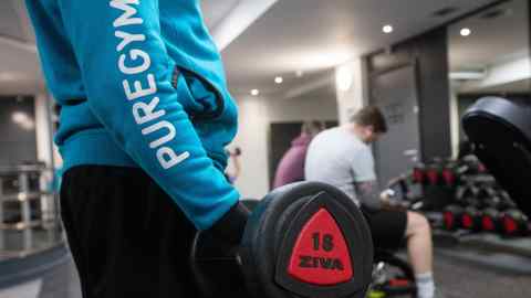 An employee holds a dumbbell weight during a work out session at a Pure Gym Ltd., a unit of CCMP Capital Advisors LLC in London, U.K., on Tuesday, Jan. 26, 2016. Pure Gym Ltd. hired Rothschild & Co as its considers 400m initial public offering, the Sunday Times reported, citing unidentified sources. Photographer: Simon Dawson/Bloomberg
