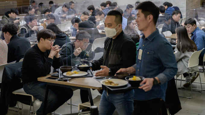 In a photo taken on April 9, 2020 employees sit behind protective screens as part of preventative measures against the COVID-19 novel coronavirus, as they eat in a cafeteria at the offices of Hyundai Card credit card company in Seoul. - Hyundai Card has implemented reduced working hours and staggered lunch breaks, while South Korea -- once grappling with the largest coronavirus outbreak outside China -- has seen a continued decline in new virus cases thanks to "aggressive tests and active participation in social distancing", authorities said. (Photo by Ed JONES / AFP) (Photo by ED JONES/AFP via Getty Images)