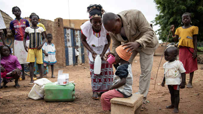 Community health workers give a child Seasonal malaria chemoprevention (SMC), in the village of Goundri, in Ziniare, north east of Burkina Faso's capital Ouagadougou on August 20, 2019. (Photo by Olympia DE MAISMONT / AFP) (Photo credit should read OLYMPIA DE MAISMONT/AFP via Getty Images)