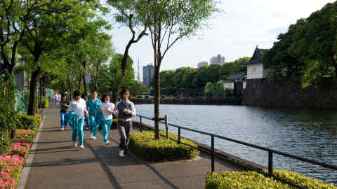 D42XXM Female joggers taking laps around 5-kilometer outer moat course surrounding Imperial Palace, site of old Edo Castle in Tokyo.