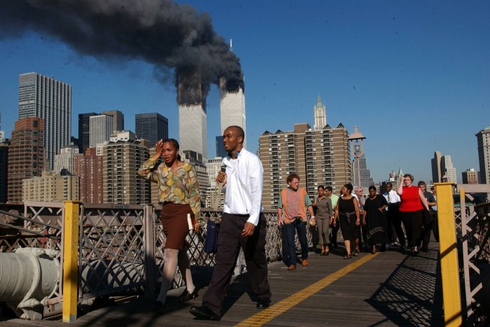 People walk over the Brooklyn Bridge as the World Trade Center burns September 11. Mr Bloomberg responded to the downturn by raising property taxes
