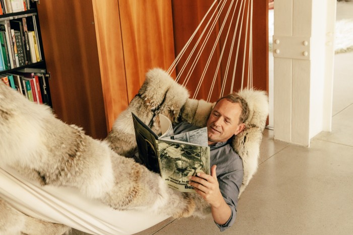 The artist reads in his Bless hammock