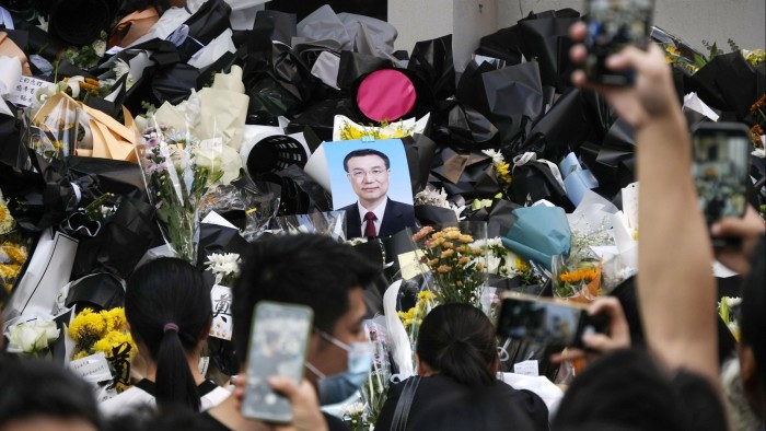 A photograph of Li sits amid bouquets laid by mourners