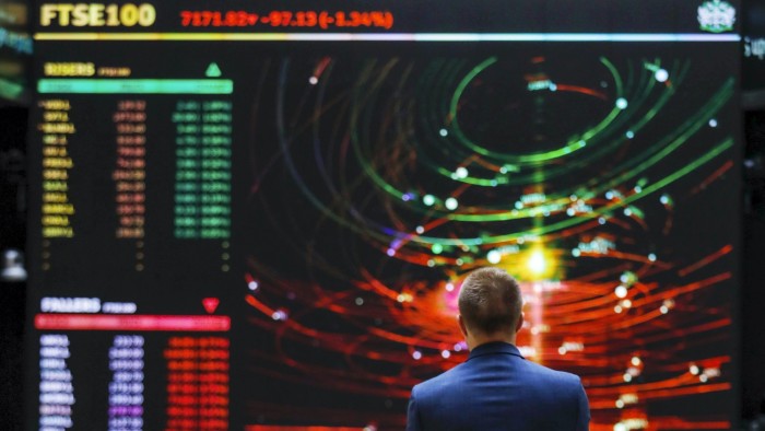 An employee views a FTSE share index board in the atrium of the London Stock Exchange Group