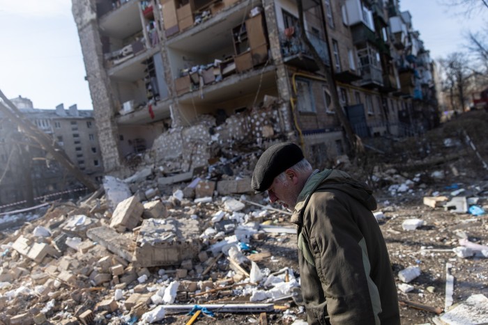 A man walks by the ruins of an apartment bloc destroyed by a bomb
