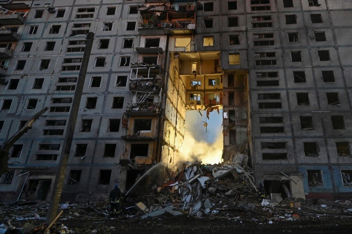 A firefighter works at a site of a residential building heavily damaged by a missile strike
