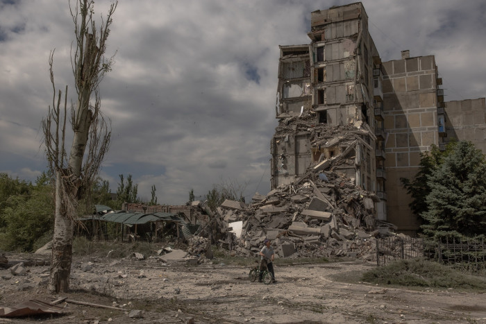 A local resident pushes a bicycle past a destroyed residential building following shelling in the town of Toretsk, eastern Donetsk region